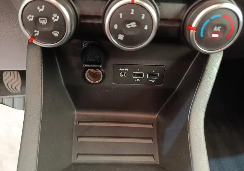 Vue rapprochée de la console centrale noire de la Renault Clio avec commandes climatisation et ports USB/Aux-In.