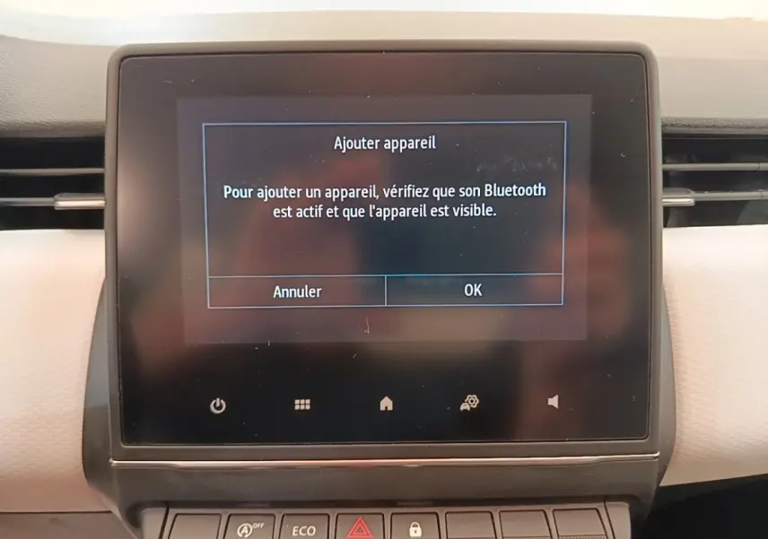 Écran tactile central affichant la connexion Bluetooth dans l'habitacle d'une Renault Clio blanche, vue de face.