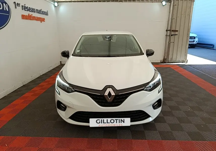 Vue avant d'une Renault Clio blanche 2023 avec phares LED allumés dans un showroom intérieur.