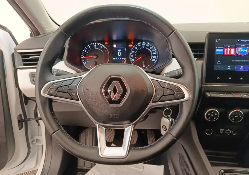 Vue rapprochée du volant cuir noir multifonctions d’une Renault Clio blanche 2023 avec tableau de bord et écran tactile.