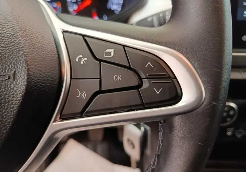 Gros plan sur le côté droit du volant cuir synthétique de la Renault Clio blanc, avec commandes multifonctions visibles.