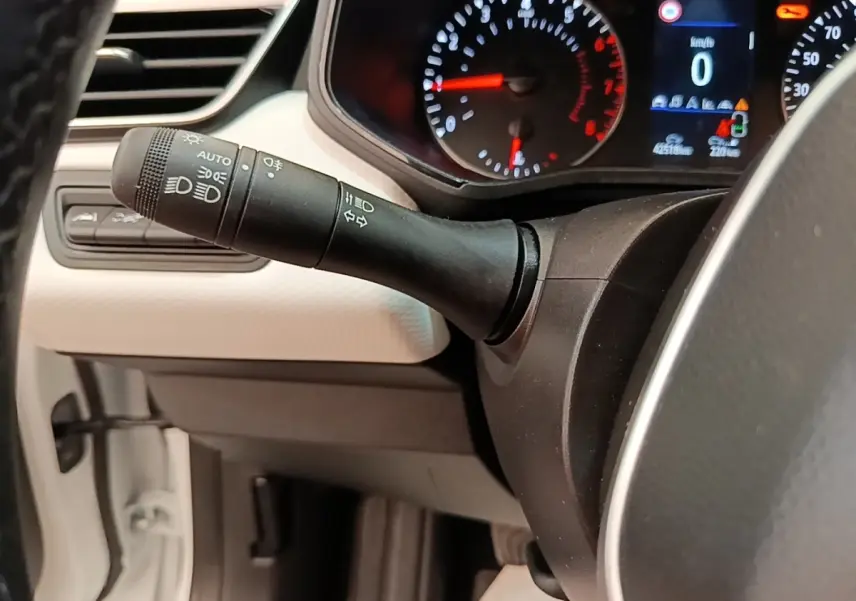 Gros plan sur la manette de commandes des phares et clignotants côté gauche du tableau de bord blanc de la Renault Clio 2023.
