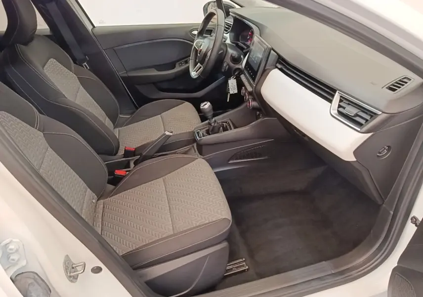 Vue intérieure côté conducteur de la Renault Clio blanche 2023, avec sièges tissu gris et tableau de bord clair.