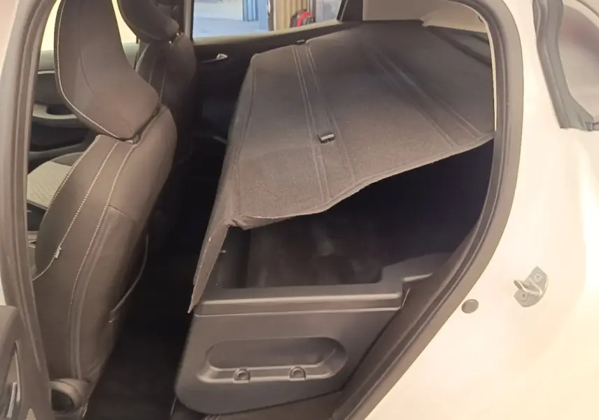 Vue côté droit arrière d'une Renault Clio blanche 2023 montrant le coffre de rangement sous le plancher relevé.