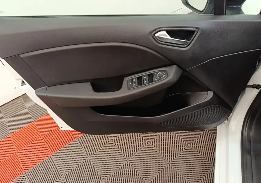 Vue intérieure de la porte avant gauche blanche de la Renault Clio 2023 avec commandes électriques et poignée argentée.