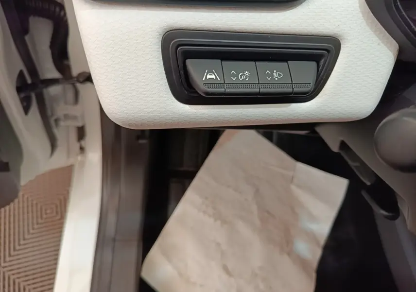Vue rapprochée des commandes d’aide à la conduite sur panneau blanc à gauche du volant dans une Renault Clio blanche 2023.