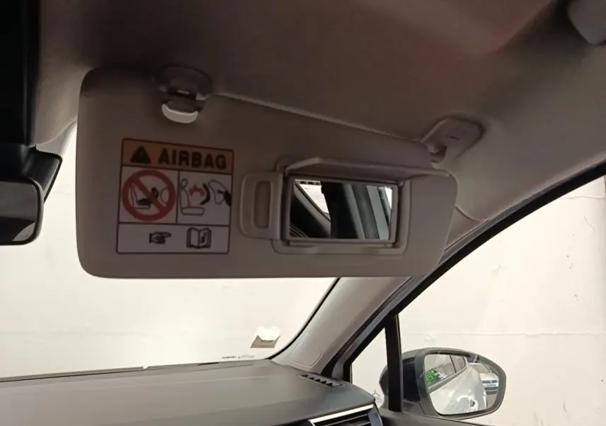 Intérieur de Renault Clio blanc 2023 vu côté passager, avec pare-soleil ouvert et miroir de courtoisie visible.