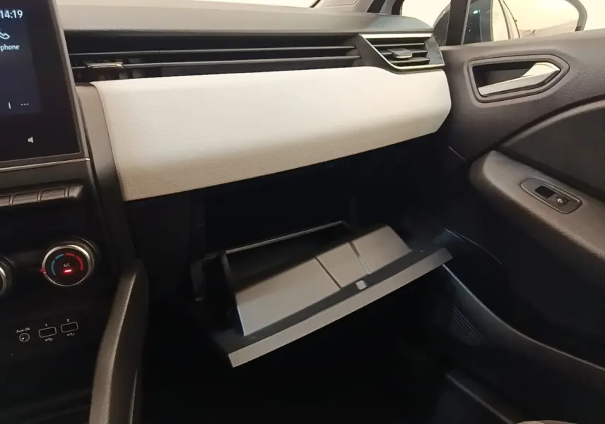 Intérieur côté passager de la Renault Clio blanc, boîte à gants ouverte et tableau de bord clair avec écran tactile.