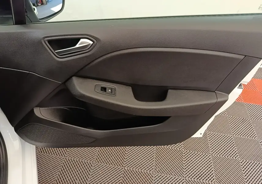 Vue rapprochée de la porte avant gauche noire d’une Renault Clio blanche, avec poignée intégrée et commande de fenêtre.