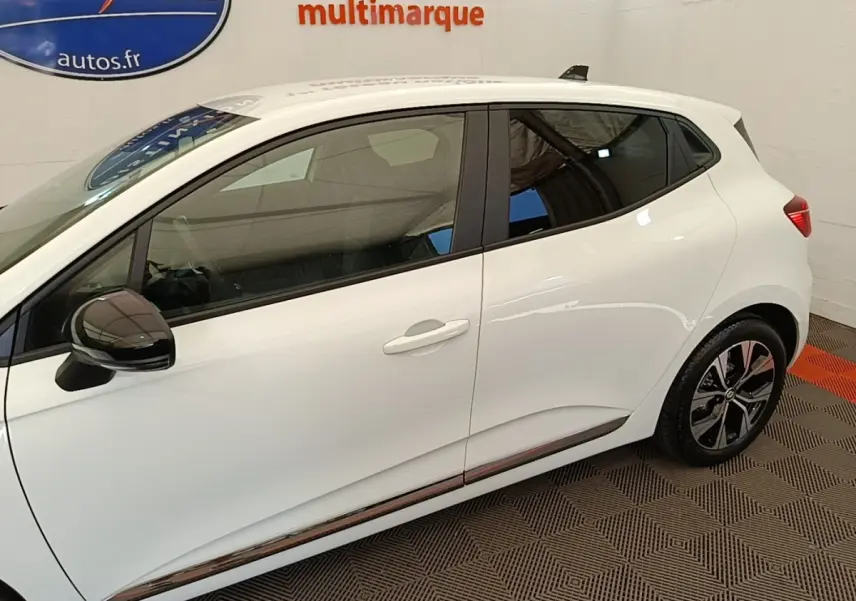 Profil côté gauche de la Renault Clio blanche 2023 avec rétroviseur noir et jantes alliage distinctives.