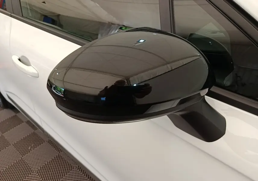 Gros plan sur le rétroviseur extérieur noir du côté gauche d'une Renault Clio blanche, version 2023.