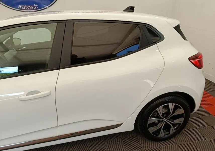 Vue latérale droite d'une Renault Clio blanche 2023 avec jantes alliage et poignées de porte intégrées.
