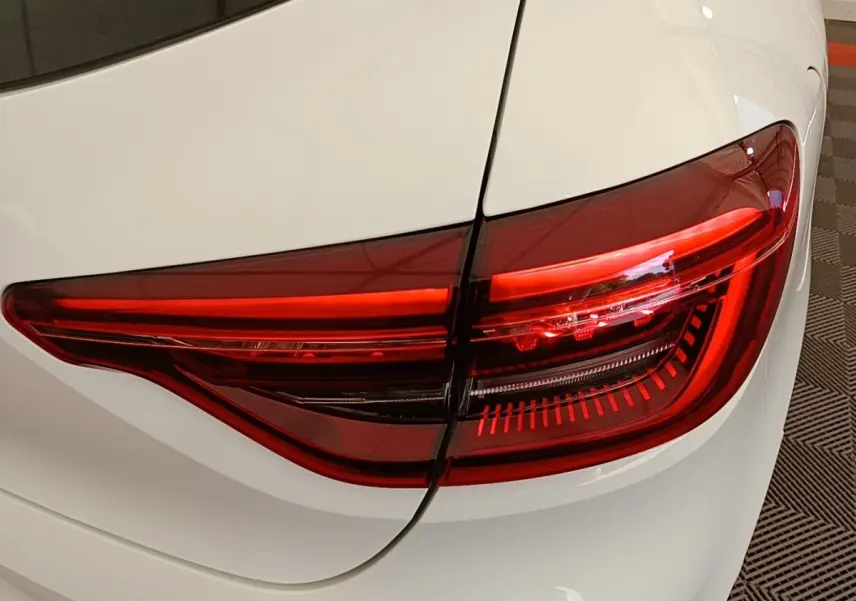 Gros plan sur le feu arrière droit rouge d’une Renault Clio blanche 2023, mettant en valeur ses lignes modernes.