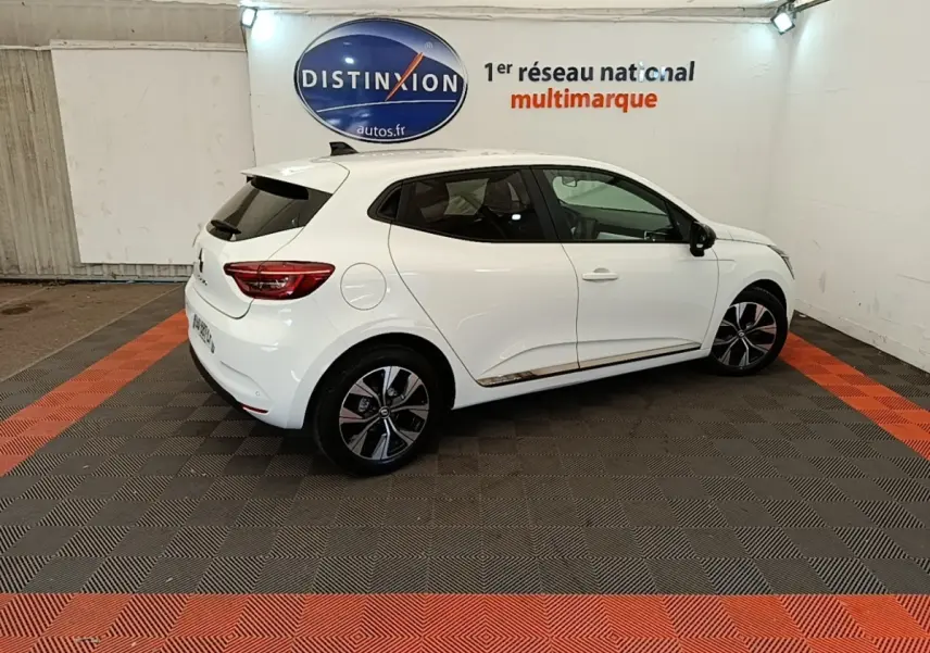 Renault Clio blanche vue de profil droit en intérieur, avec jantes alliage et vitres teintées.