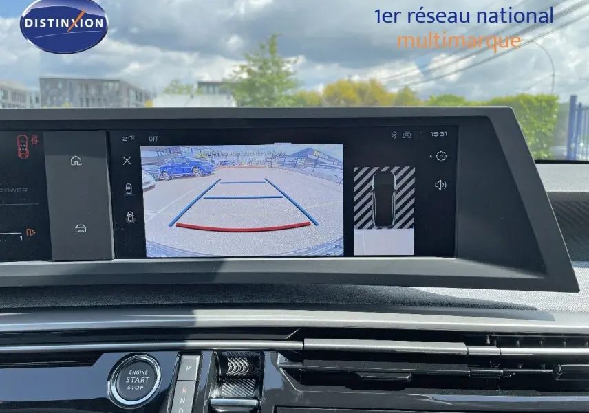 Vue intérieure du tableau de bord du Peugeot 3008 Hybrid bleu Ingaro Metal avec écran de caméra de recul et commandes modernes.