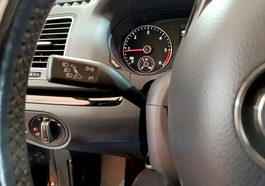 Gros plan intérieur sur le volant et le commodo de clignotant du Volkswagen Sharan 2.0 TDI marron, tableau de bord visible.