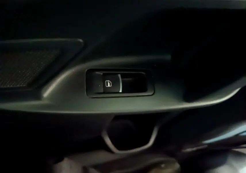 Gros plan sur le bouton de verrouillage centralisé noir dans l'habitacle sombre d'un Volkswagen Sharan marron.