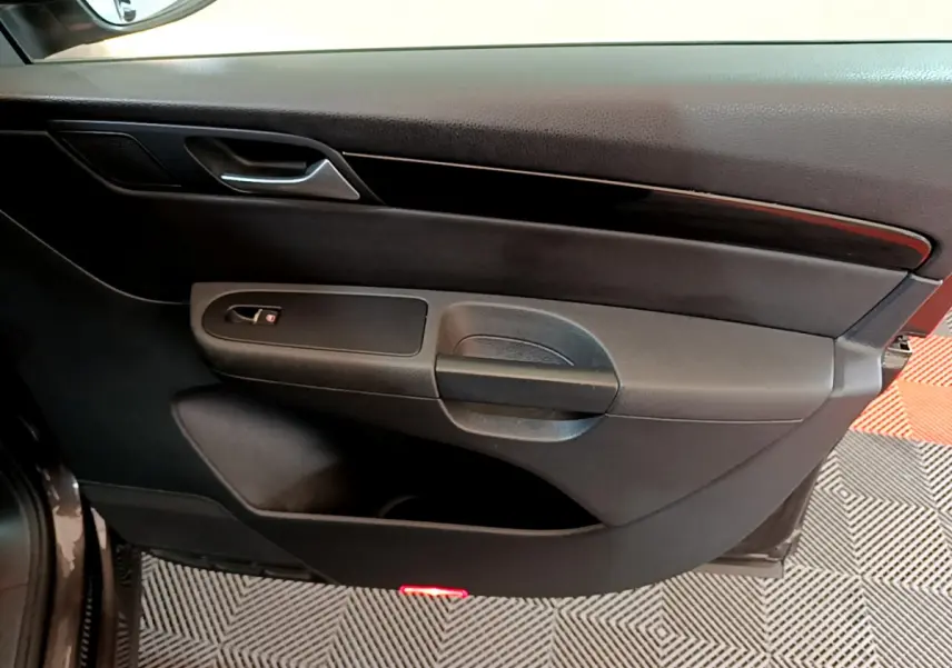 Vue rapprochée de la porte intérieure côté droit du Volkswagen Sharan marron, avec poignée et bande décorative noire.