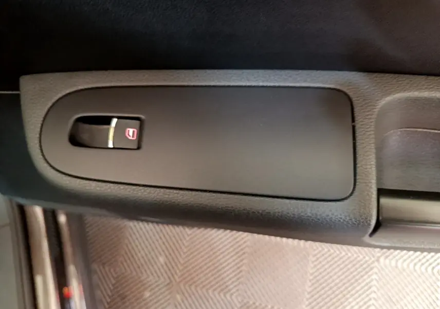 Gros plan sur la commande de verrouillage centralisé noire dans l’habitacle du Volkswagen Sharan marron.