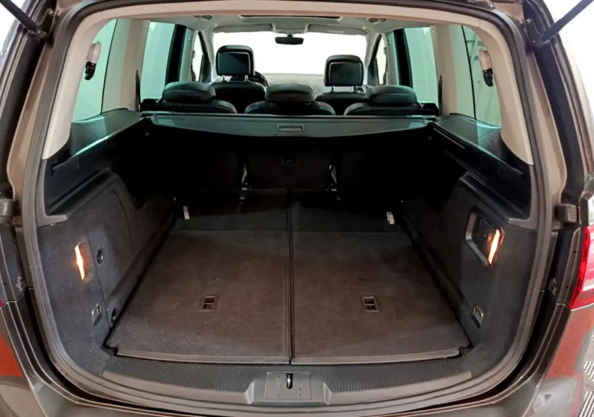Vue arrière du coffre ouvert d’un Volkswagen Sharan marron 2017, montrant l’espace de chargement avec sièges rabattus et plancher plat.