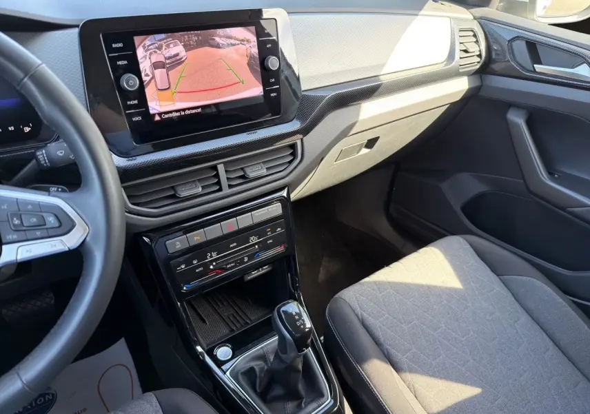 Vue intérieure côté passager du tableau de bord et console centrale noire du Volkswagen T-Cross 2025 avec écran tactile affichant la caméra de recul.