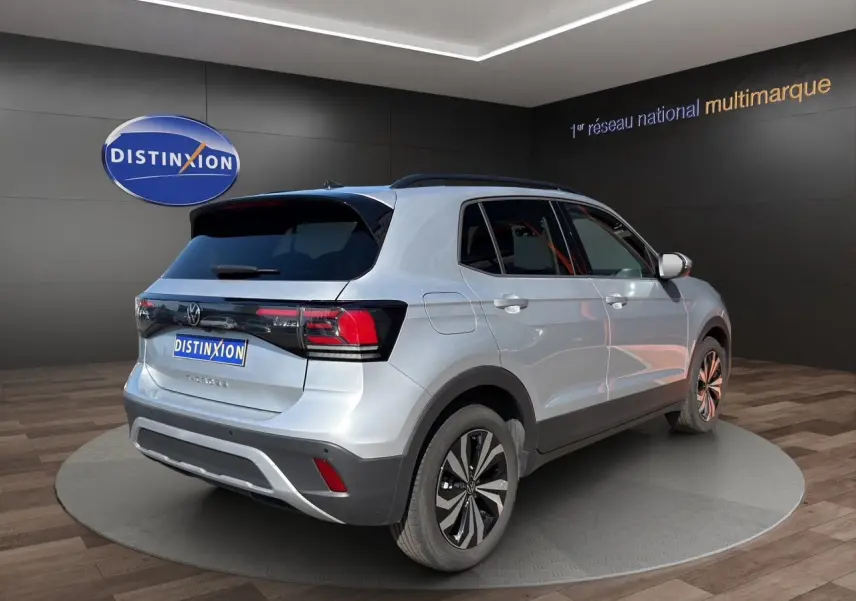 Vue 3/4 arrière droite d'un Volkswagen T-Cross 2025 reflet d'argent avec jantes alliage et vitres surteintées.