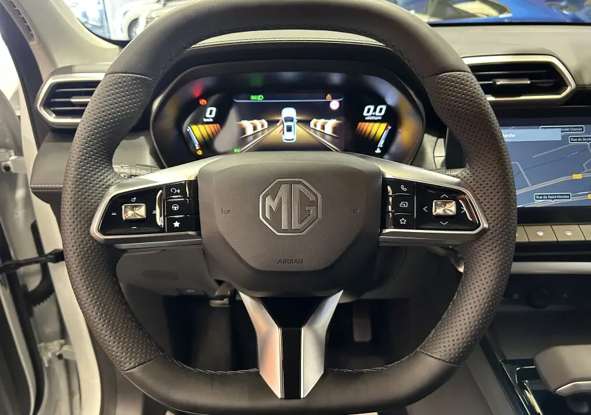 Vue centrée sur le volant cuir perforé de la MG ZS 1.5 Hybrid+ 197 Luxury avec tableau de bord numérique et écran GPS.
