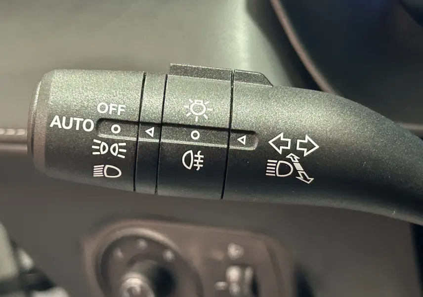 Gros plan sur la commande de phares et clignotants du MG ZS 1.5 Hybrid+ 197 Luxury en intérieur noir.