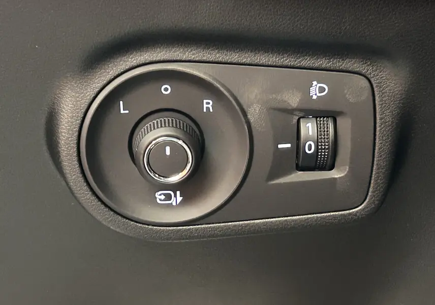 Gros plan sur les commandes noires de réglage des rétroviseurs et de l'inclinaison des phares dans l'habitacle du MG ZS Dover White.