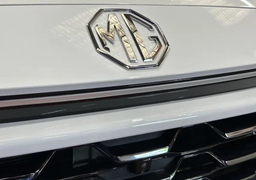 Gros plan sur la calandre blanche du MG ZS 1.5 Hybrid+ 197 Luxury avec logo chromé MG et caméra 360° intégrée.