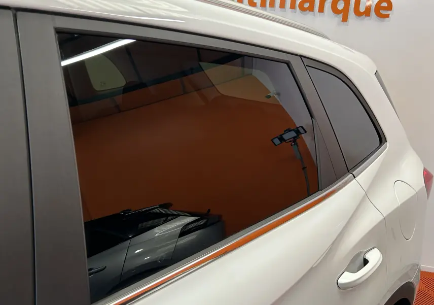 Vue latérale droite du MG ZS 1.5 Hybrid+ 197 Luxury en blanc Dover, avec vitres teintées et poignée de porte visible.