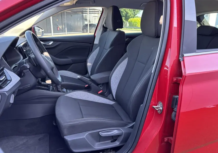Intérieur avant droit d'une Skoda Scala 2024 rouge velvet metal, sièges tissu noir et gris avec surpiqûres claires.