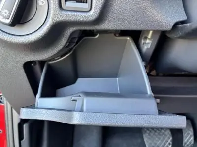 Gros plan sur le rangement ouvert sous le tableau de bord d'une Skoda Scala rouge Velvet Metal, côté conducteur.