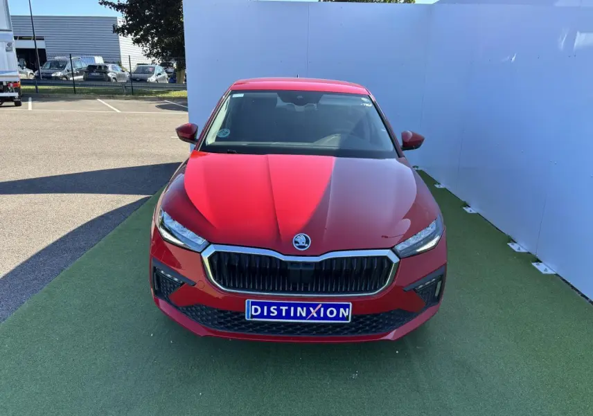 Vue frontale d'une Skoda Scala 2024 rouge velvet metal avec calandre noire et phares LED allumés.