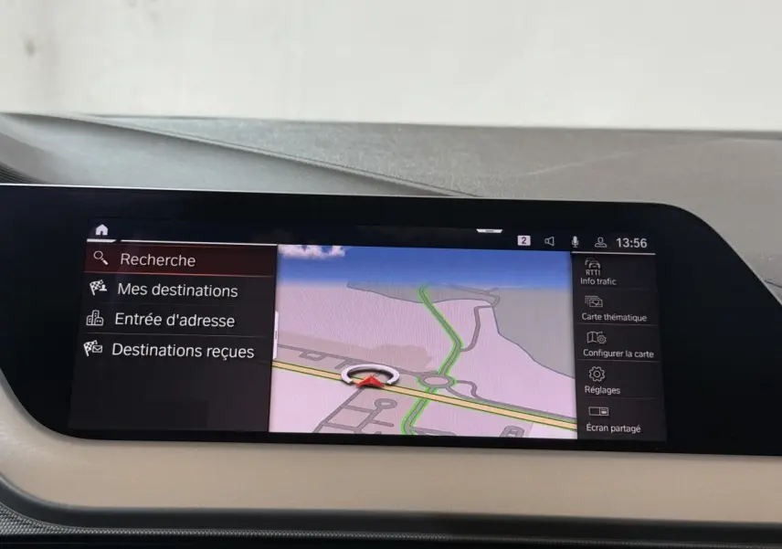 Écran tactile central de navigation affichant une carte, dans l’habitacle beige d’une BMW Série 1 noire.