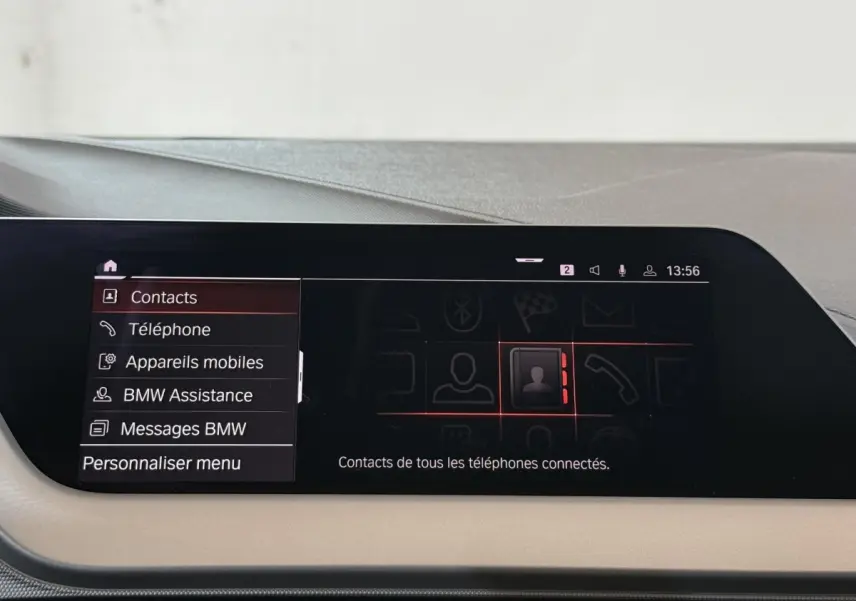 Écran tactile central de la BMW Série 1 116d Business Design 2022 affichant le menu contacts en intérieur noir et beige.