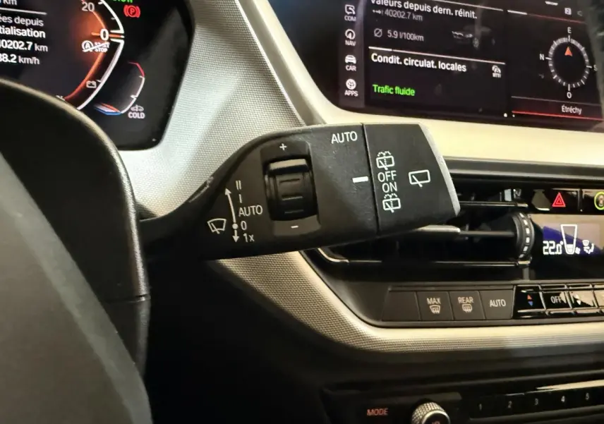 Gros plan sur la commande d’essuie-glace à gauche du volant dans l’habitacle noir et beige de la BMW Série 1 116d.