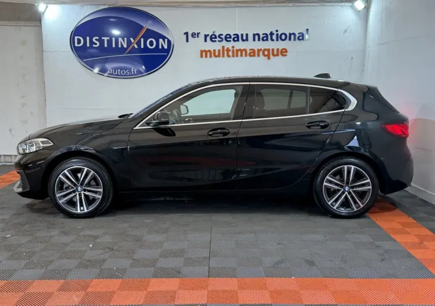 Vue de profil côté gauche d'une BMW Série 1 116d Business Design noire, avec jantes alliage et feux arrière LED visibles.