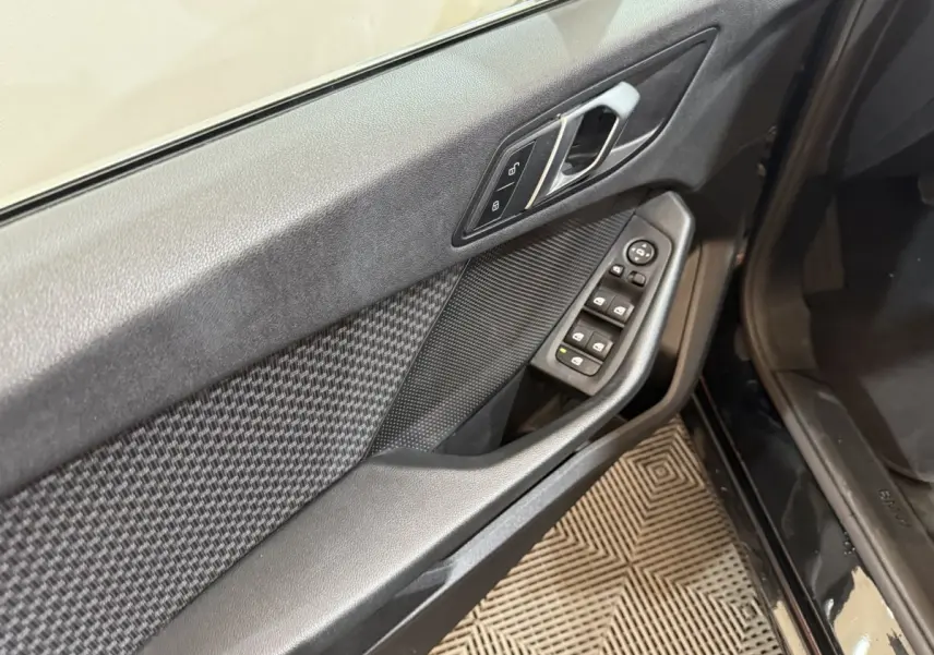 Vue rapprochée de la porte avant gauche noire de la BMW Série 1 116d avec commandes électriques et poignée argentée.