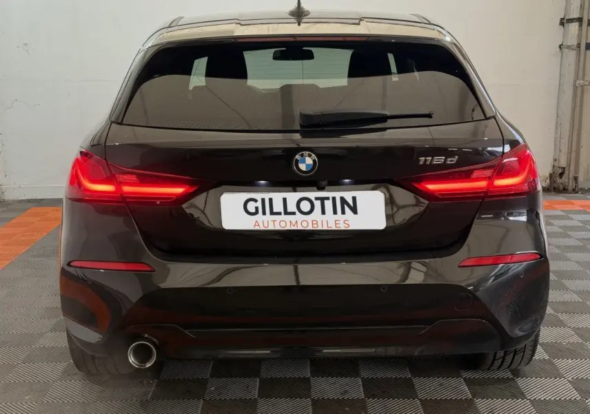 Vue arrière d'une BMW Série 1 116d noire avec feux LED allumés et sortie d'échappement visible côté gauche.