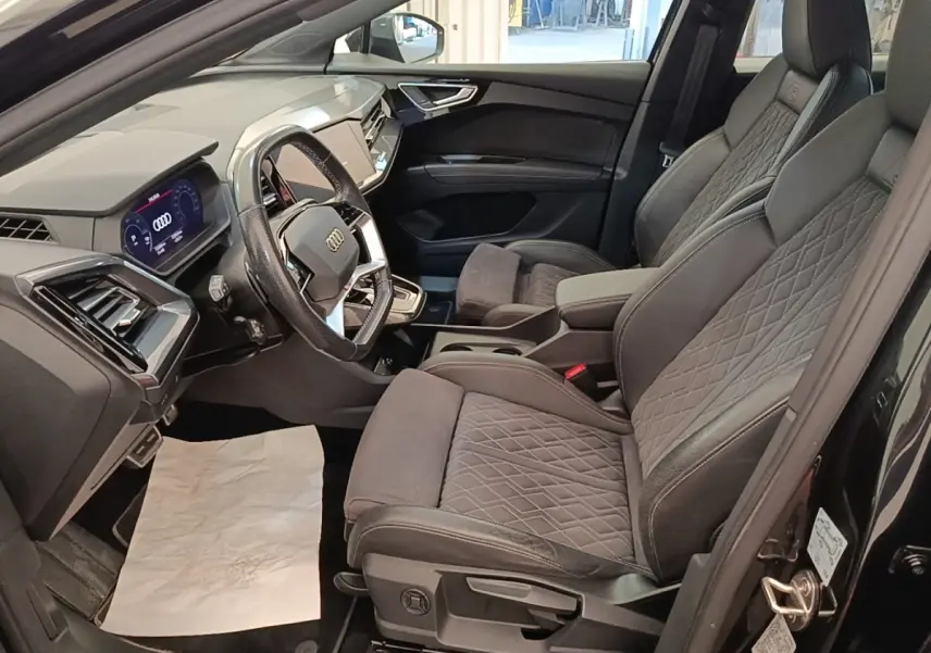 Intérieur côté conducteur de l’Audi Q4 E-TRON Sportback noir 2023, sièges S Line en cuir et alcantara, tableau de bord digital.