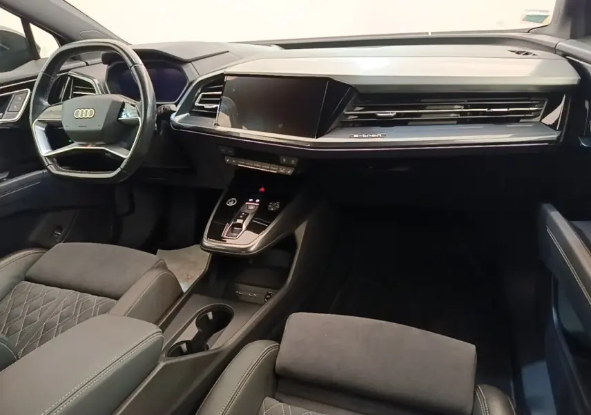 Intérieur noir de l'Audi Q4 E-TRON Sportback 2023, vue du tableau de bord et volant multifonctions côté conducteur.