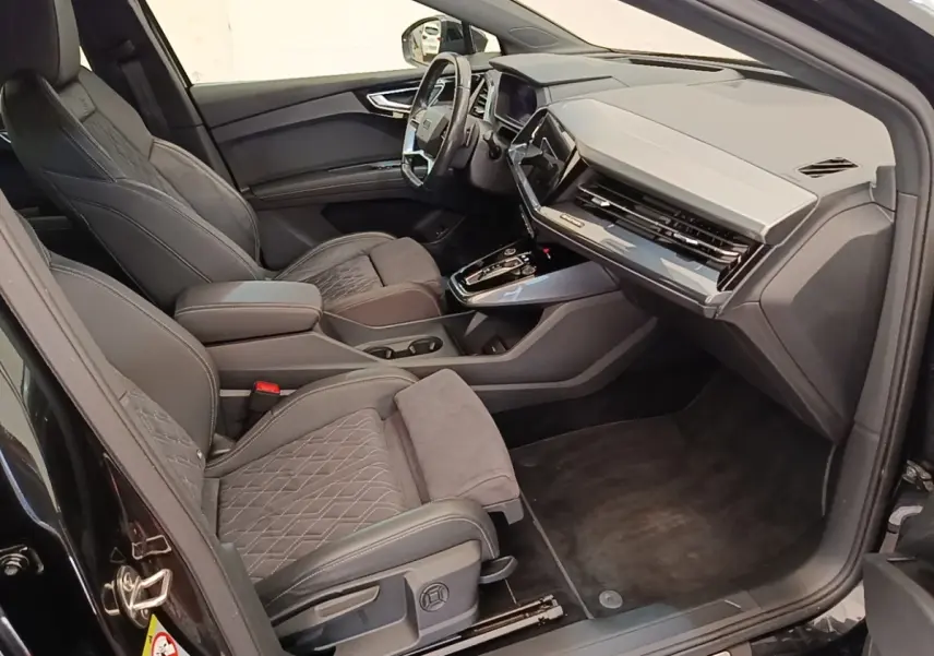 Intérieur Audi Q4 E-TRON Sportback noir, vue côté droit montrant sièges en cuir et tableau de bord moderne.