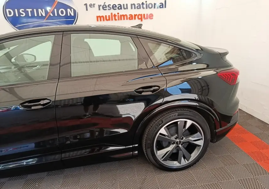 Vue latérale droite d’un Audi Q4 E-TRON Sportback noir, mettant en valeur la ligne de toit plongeante et les feux arrière LED.