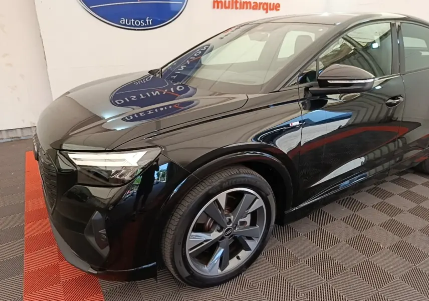 Audi Q4 E-Tron Sportback noir en 3/4 avant droit, mettant en valeur ses jantes et phares LED distinctifs.