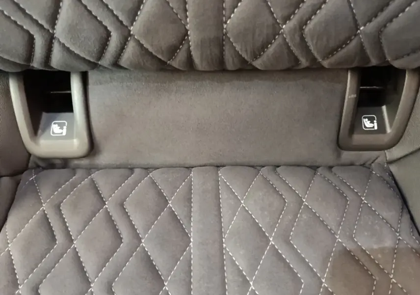 Détail des commandes de rabattement des sièges arrière sur tissu noir matelassé de l'Audi Q4 E-TRON Sportback.