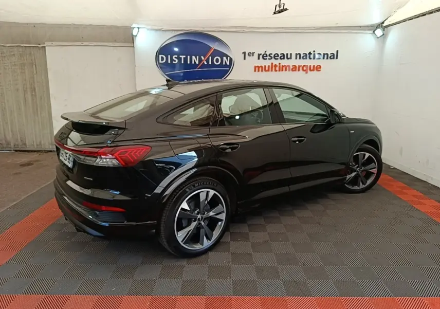 Audi Q4 E-Tron Sportback électrique noir, vue 3/4 arrière droit, avec jantes S Line et toit plongeant.