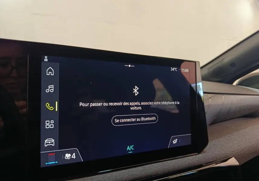 Écran tactile central de la Renault Clio bleu, affichant la connexion Bluetooth dans l'habitacle côté droit.