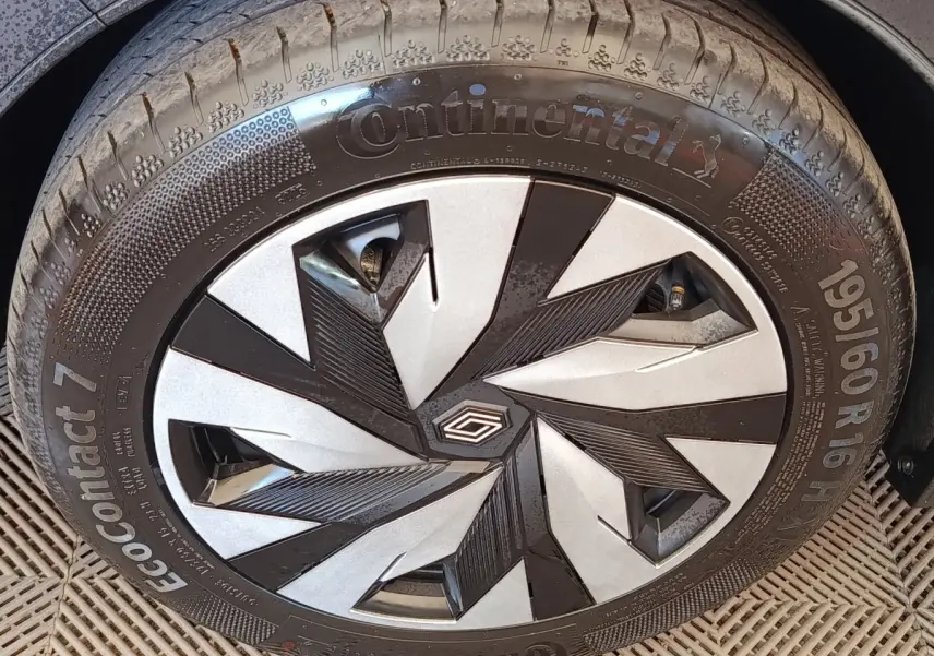 Gros plan sur la roue avant droite de la Renault Clio bleu, avec jante au design géométrique noir et argent.