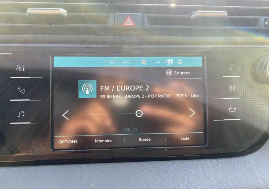 Écran tactile central de la Citroën C4 Spacetourer blanc, affichant la radio FM Europe 2 en plein jour.